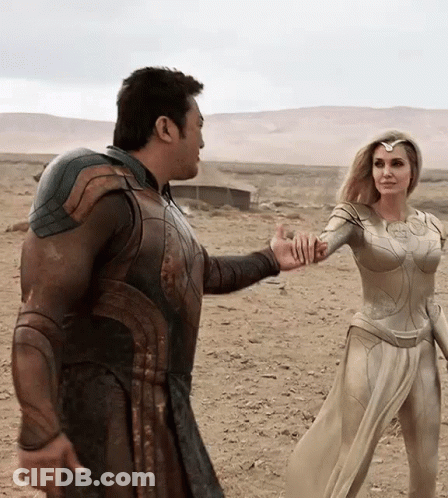 A Man And A Woman Are Standing In The Desert Holding Hands . GIF