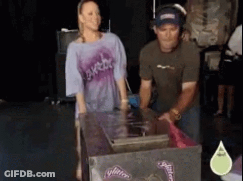 A Man And A Woman Are Standing Next To A Box That Says Glitter On It GIF
