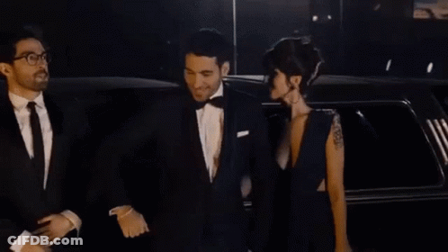 A Man And A Woman Are Standing Next To A Limousine . GIF