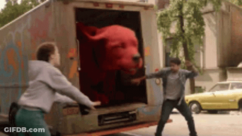 A Man And A Woman Are Standing Next To A Truck With A Stuffed Animal In The Back . GIF