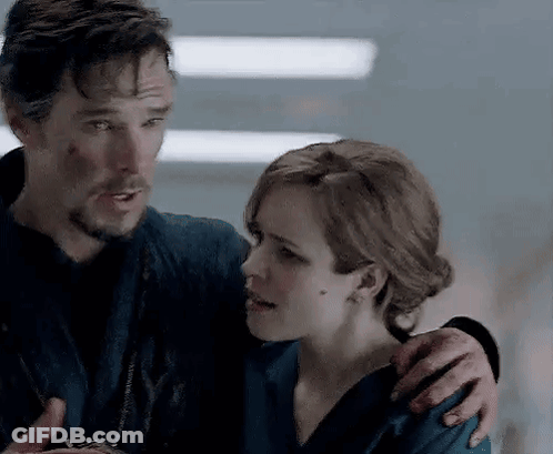 A Man And A Woman Are Standing Next To Each Other And Hugging . GIF