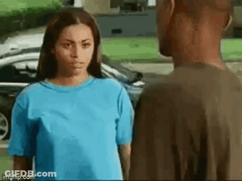 A Man And A Woman Are Standing Next To Each Other And Looking At Each Other . GIF