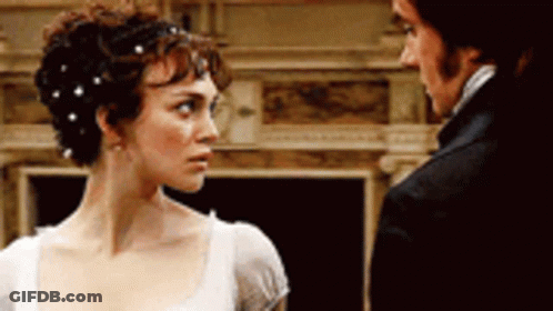 A Man And A Woman Are Standing Next To Each Other And Looking At Each Other GIF