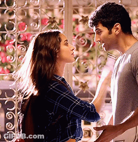 A Man And A Woman Are Standing Next To Each Other And Looking At Each Other In Front Of A Window . GIF