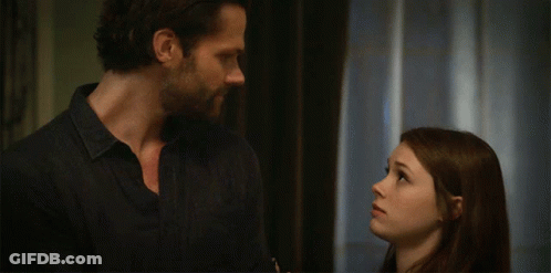 A Man And A Woman Are Standing Next To Each Other And Looking At Each Other GIF