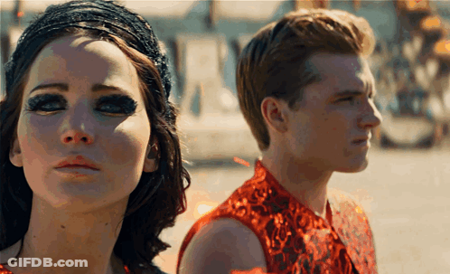 A Man And A Woman Are Standing Next To Each Other And Looking At The Camera GIF