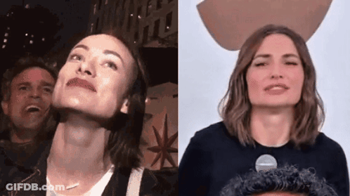 A Man And A Woman Are Standing Next To Each Other And Looking Up At The Sky . GIF