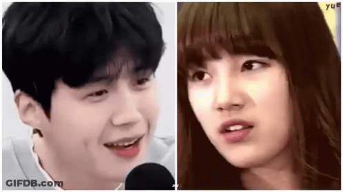 A Man And A Woman Are Standing Next To Each Other And Smiling At Each Other . GIF