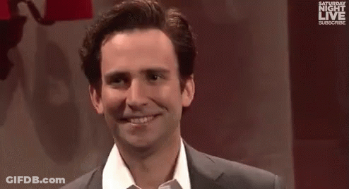 A Man And A Woman Are Standing Next To Each Other And Smiling At The Camera . GIF