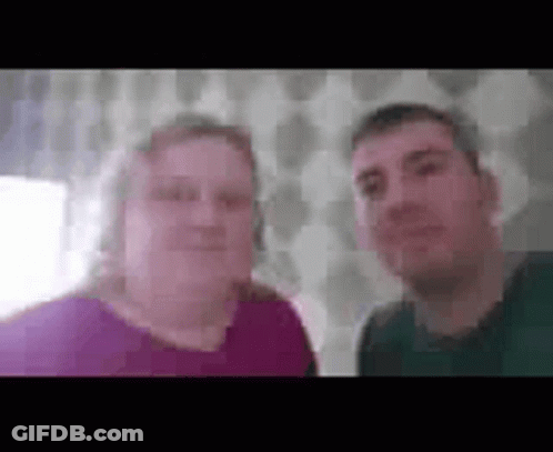 A Man And A Woman Are Standing Next To Each Other And Smiling For A Picture . GIF