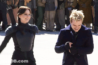 A Man And A Woman Are Standing Next To Each Other And Smiling In Front Of A Crowd GIF