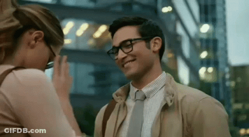 A Man And A Woman Are Standing Next To Each Other And Smiling . GIF