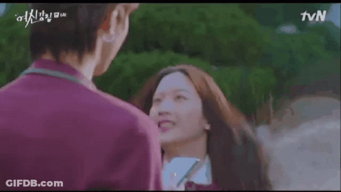 A Man And A Woman Are Standing Next To Each Other And Smiling . The Woman Is Wearing A School Uniform . GIF