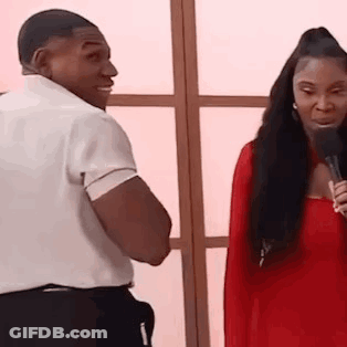A Man And A Woman Are Standing Next To Each Other And Talking Into Microphones . GIF