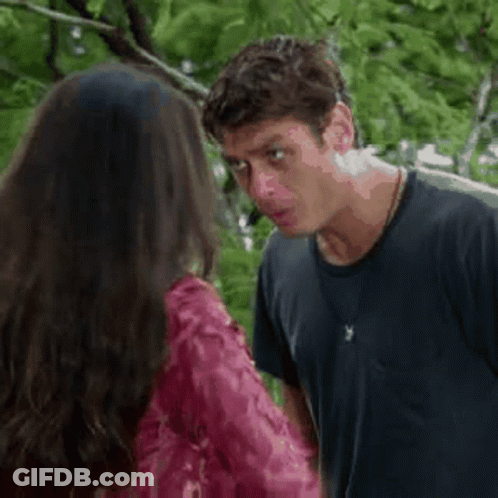 A Man And A Woman Are Standing Next To Each Other And Talking . The Woman Is Wearing A Red Dress . GIF