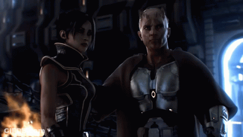 A Man And A Woman Are Standing Next To Each Other And The Man Has An O On His Chest GIF