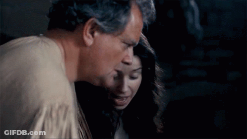 A Man And A Woman Are Standing Next To Each Other And The Man Is Kissing The Woman On The Cheek . GIF
