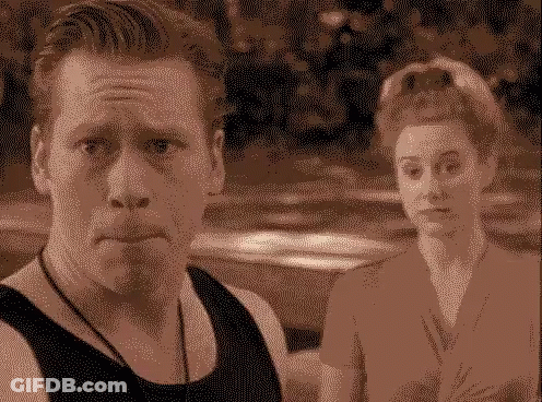 A Man And A Woman Are Standing Next To Each Other And The Man Is Making A Face GIF