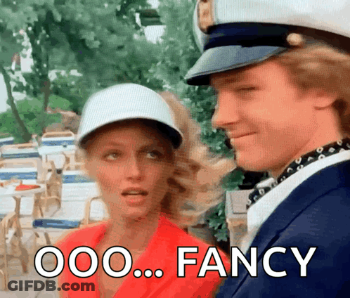 A Man And A Woman Are Standing Next To Each Other And The Man Is Wearing A Captain 'S Hat .. GIF