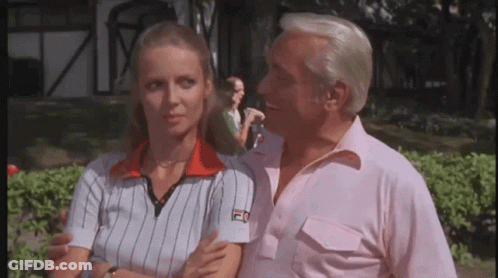 A Man And A Woman Are Standing Next To Each Other And The Man Is Wearing A Fila Shirt . GIF