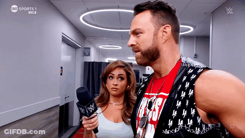 A Man And A Woman Are Standing Next To Each Other And The Man Is Wearing A Vest That Says Tnt Sports GIF