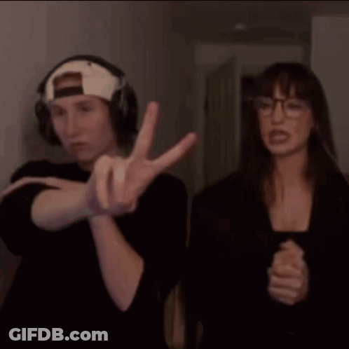 A Man And A Woman Are Standing Next To Each Other And The Man Is Wearing Headphones And The Woman Is Wearing Glasses GIF