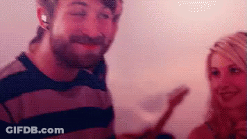 A Man And A Woman Are Standing Next To Each Other And The Man Is Wearing Headphones GIF