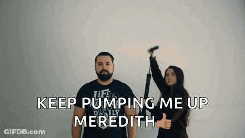 A Man And A Woman Are Standing Next To Each Other And The Woman Is Giving A Thumbs Up Sign GIF