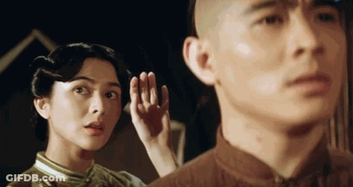 A Man And A Woman Are Standing Next To Each Other And The Woman Is Listening To The Man 'S Ear . GIF