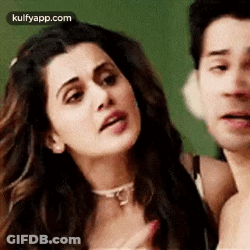 A Man And A Woman Are Standing Next To Each Other And The Woman Is Making A Funny Face . GIF