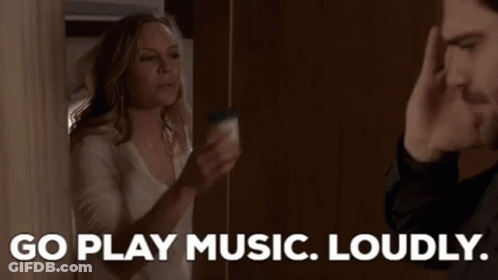 A Man And A Woman Are Standing Next To Each Other And The Woman Is Saying `` Go Play Music Loudly '' GIF