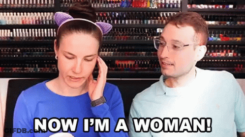 A Man And A Woman Are Standing Next To Each Other And The Woman Is Saying Now I 'M A Woman GIF