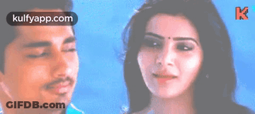 A Man And A Woman Are Standing Next To Each Other And The Woman Is Smiling . GIF
