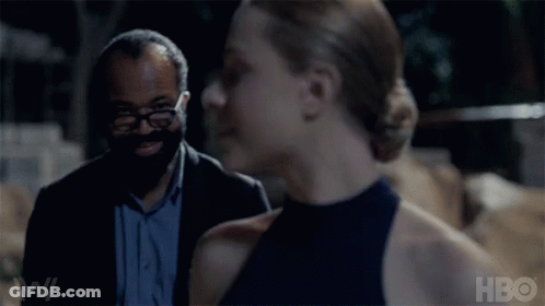 A Man And A Woman Are Standing Next To Each Other And The Woman Is Smiling While The Man Looks On . GIF