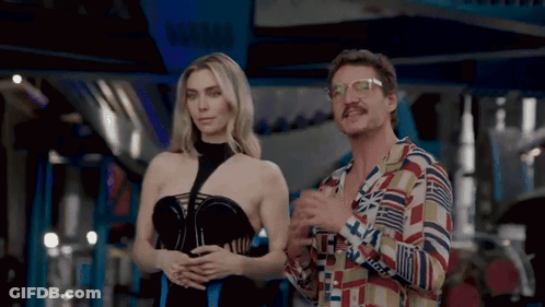 A Man And A Woman Are Standing Next To Each Other And The Woman Is Wearing A Black Dress GIF