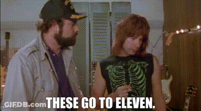 A Man And A Woman Are Standing Next To Each Other And The Woman Is Wearing A Skeleton Tank Top . GIF
