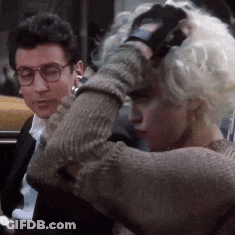 A Man And A Woman Are Standing Next To Each Other And The Woman Is Wearing Gloves GIF