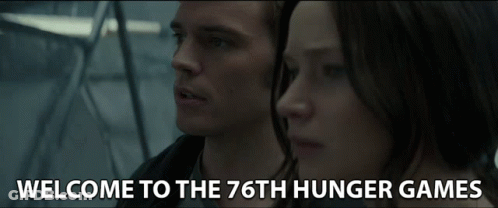 A Man And A Woman Are Standing Next To Each Other And The Words Welcome To The 76Th Hunger Games Are On The Screen GIF
