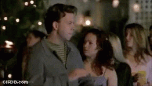 A Man And A Woman Are Standing Next To Each Other At A Party . GIF