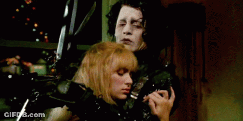A Man And A Woman Are Standing Next To Each Other Holding A Pair Of Scissors . GIF