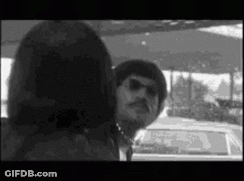 A Man And A Woman Are Standing Next To Each Other In A Car . GIF