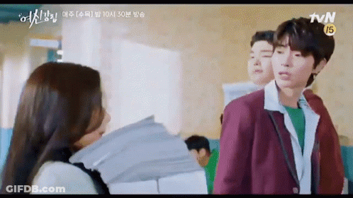 A Man And A Woman Are Standing Next To Each Other In A Classroom . GIF