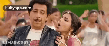 A Man And A Woman Are Standing Next To Each Other In A Crowd Of People . GIF