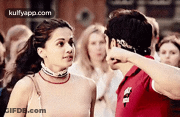 A Man And A Woman Are Standing Next To Each Other In A Crowd Of People . GIF