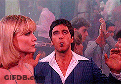 A Man And A Woman Are Standing Next To Each Other In A Crowd . GIF