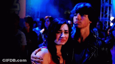 A Man And A Woman Are Standing Next To Each Other In A Crowded Room . GIF