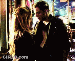 A Man And A Woman Are Standing Next To Each Other In A Dark Room GIF