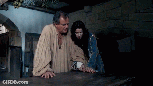 A Man And A Woman Are Standing Next To Each Other In A Dark Room GIF