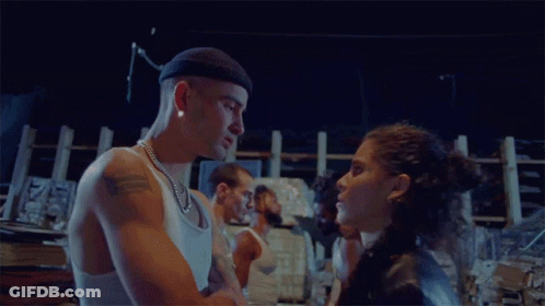 A Man And A Woman Are Standing Next To Each Other In A Dark Room GIF