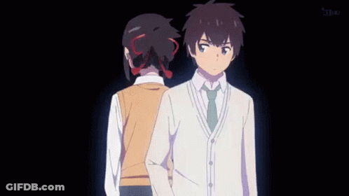 A Man And A Woman Are Standing Next To Each Other In A Dark Room . GIF